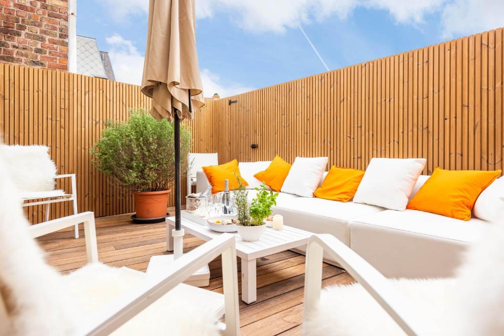 um pátio com um sofá branco e almofadas laranja em Villa Harbour - apartment for 9 people in Nieuwpoort em Nieuwpoort