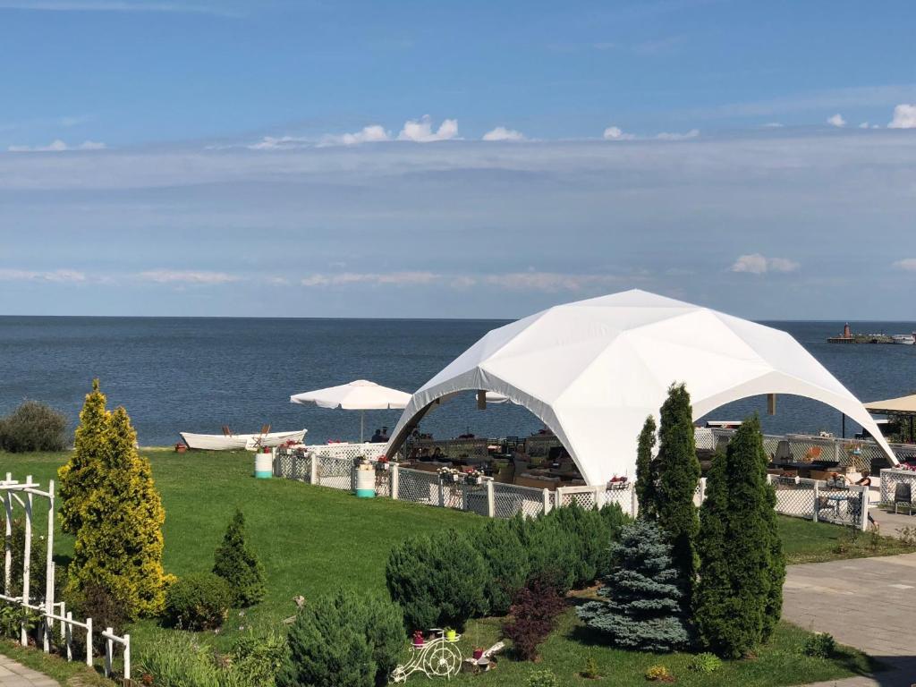 a white tent in a field near the ocean at Altrimo Hotel in Rybachiy