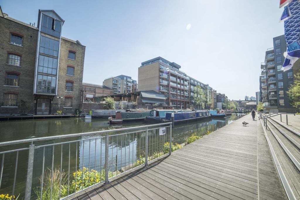 a wooden walkway next to a river with buildings at D8 - Canal View Apartment in London