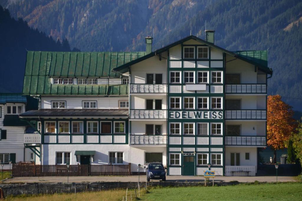 a large white building with a green roof at Pension Edelweiss Top21 in Gosau