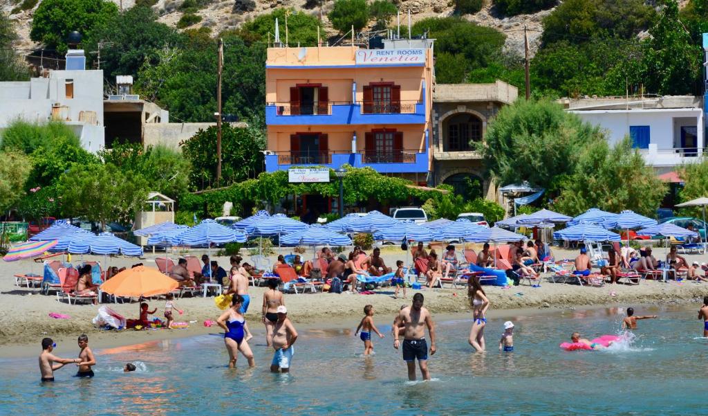 een menigte mensen op een strand met blauwe parasols bij Venetia in Tsoútsouros