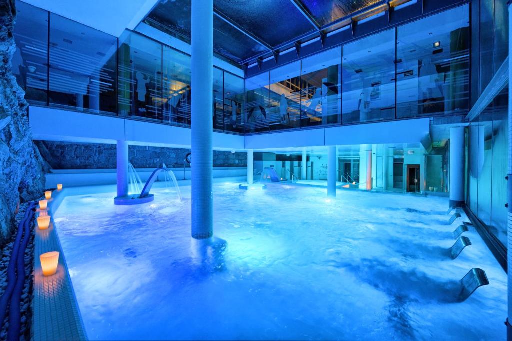 a large swimming pool in a building at night at Hotel Balneario La Hermida in La Hermida