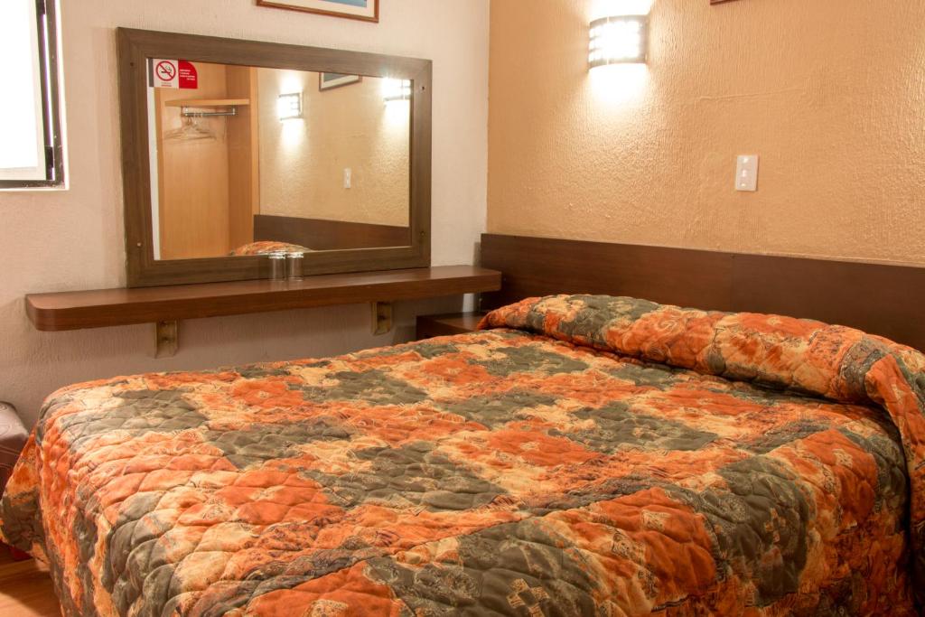 A double bed is set beside a wall-mounted dressing shelf and a large mirror.