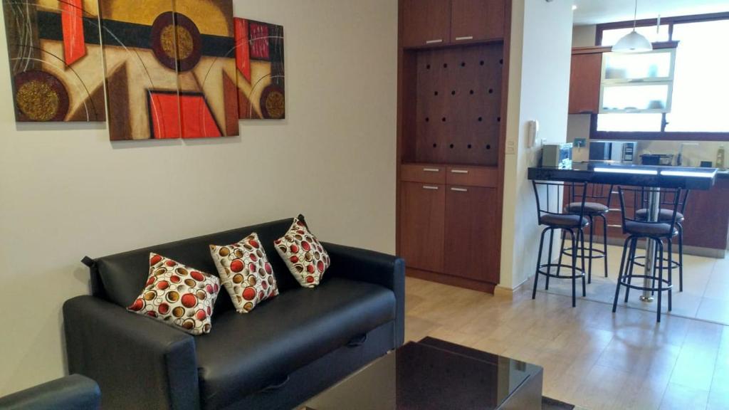 a living room with a couch and a kitchen with a bar at Torre Isos in Cochabamba