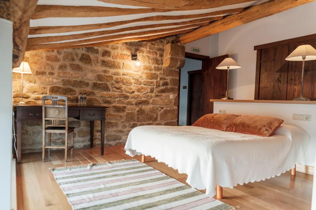 a bedroom with a bed and a stone wall at Casa Baquedano in Murugarren