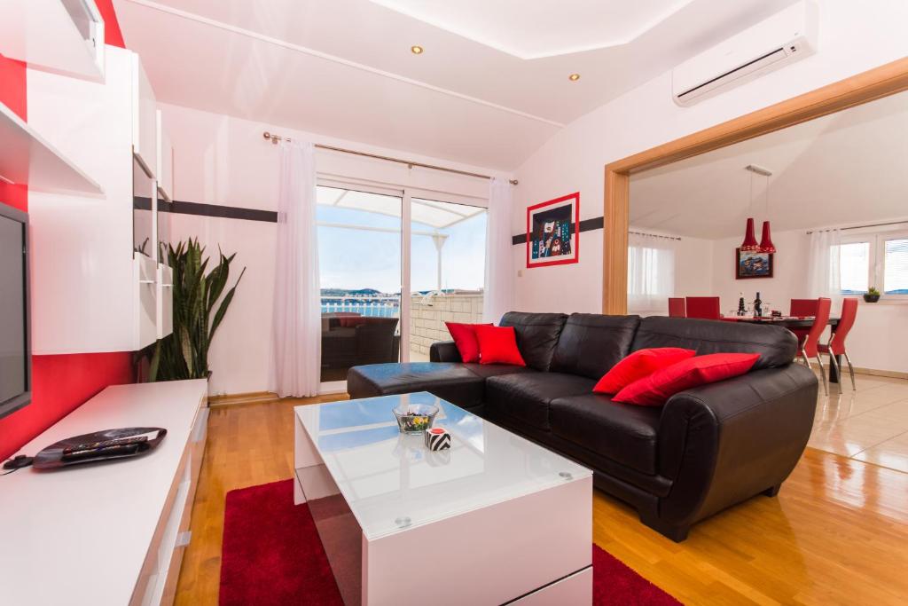 sala de estar con sofá de cuero negro y almohadas rojas en Apartments Barba, en Trogir