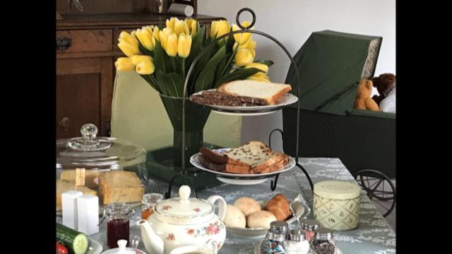 Bed and breakfast devijfbees في باريندريخت: طاولة مع طبقين من الطعام و مزهرية مع الزهور الصفراء