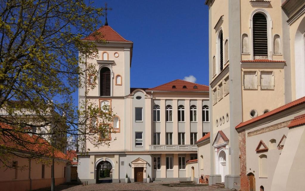 un grand bâtiment blanc avec une tour d'horloge dans une ville dans l'établissement Villa Kaunensis, à Kaunas