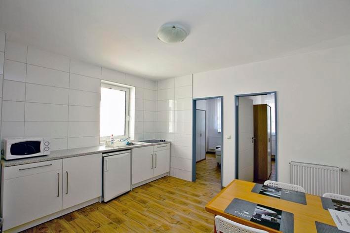 ブレーマーハーフェンにあるFeWo`s Katharinaの白いキャビネットとテーブル付きのキッチンが備わります。