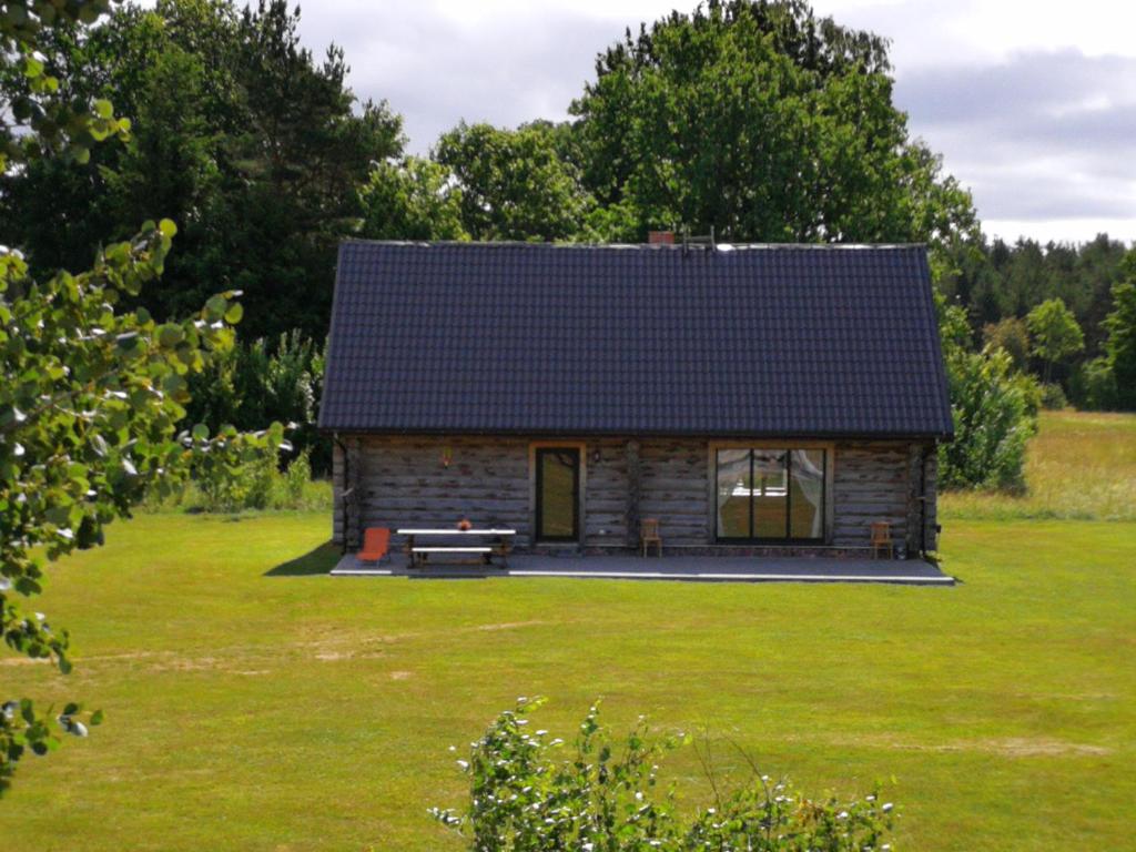 a log cabin in a field with a green yard at Palmas in Jūrkalne