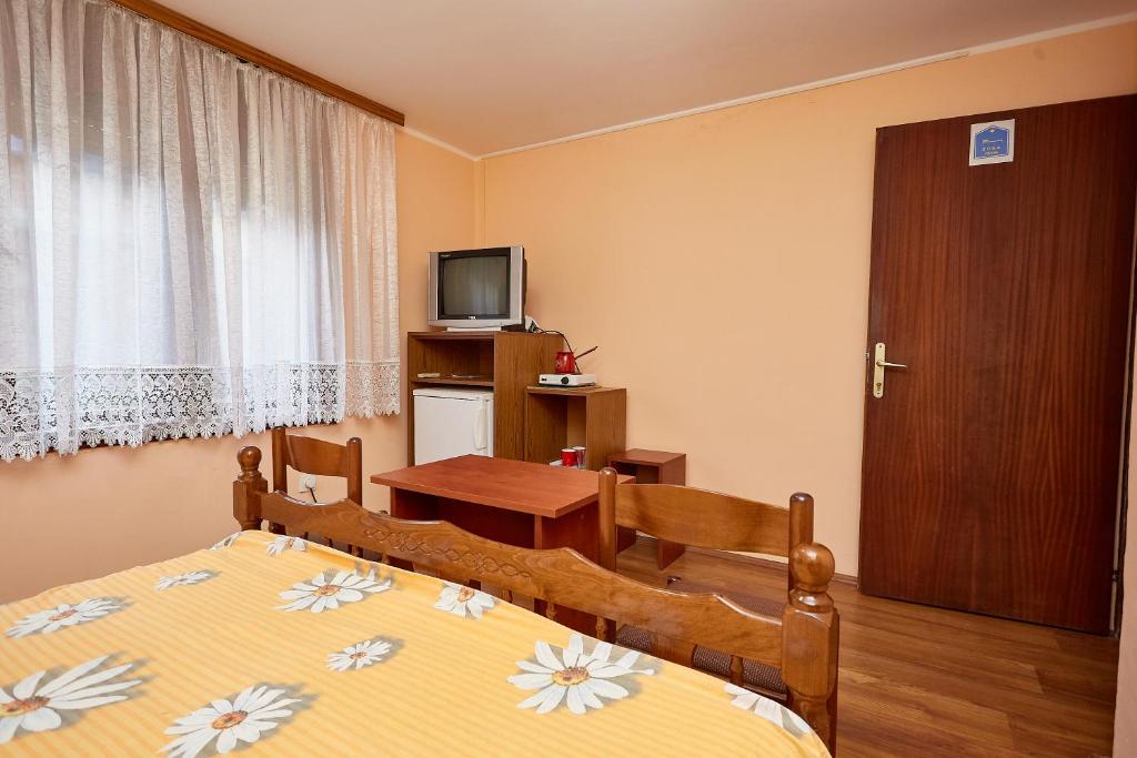 a bedroom with a bed and a table and a television at Apartmani Malica in Soko Banja