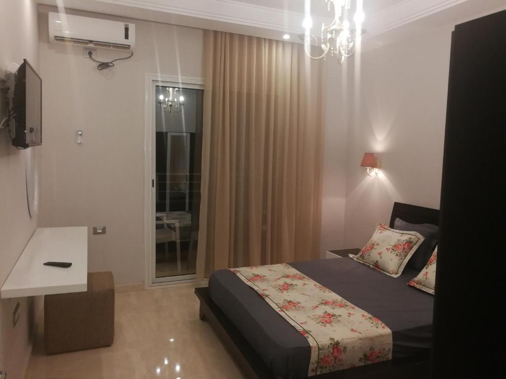 1 dormitorio con cama y lámpara de araña en London House en Bizerte