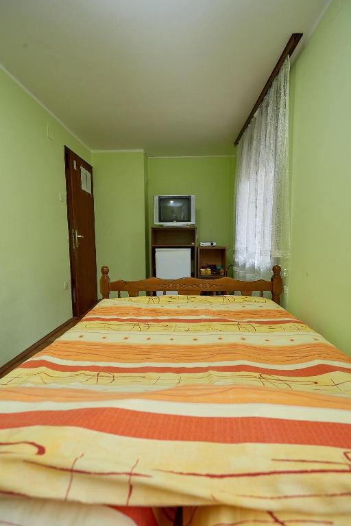 a large bed in a green room with a television at Apartmani Malica in Soko Banja