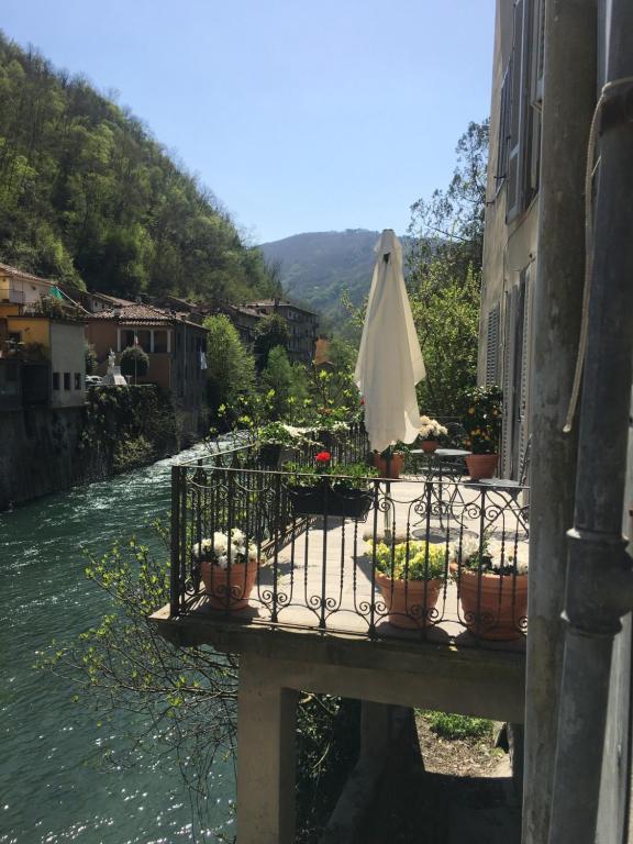 een tafel met een paraplu en potplanten naast een rivier bij Casa Ella in Bagni di Lucca