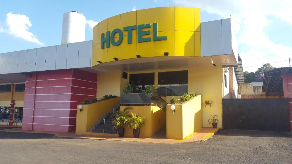 a hotel with a yellow and pink building at Hotel Peroza Corbelia in Corbélia