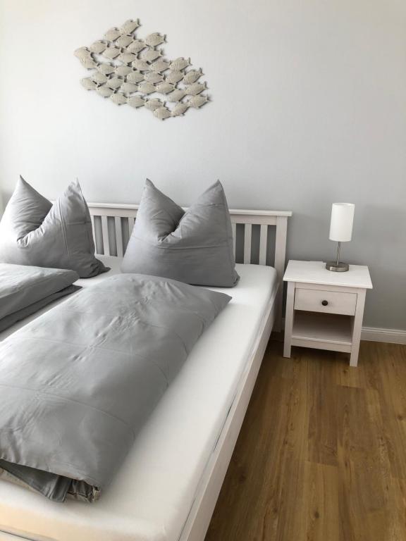 uma cama com almofadas cinzentas num quarto em Strandhütte em Norddeich