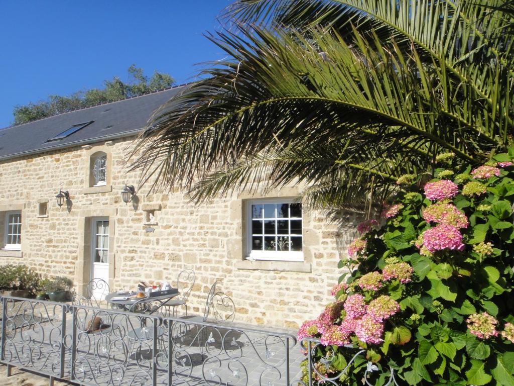 un edificio in mattoni con tavolo e palma di Gîte La Bourgetterie Fontenay sur Mer a Fontenay-sur-Mer
