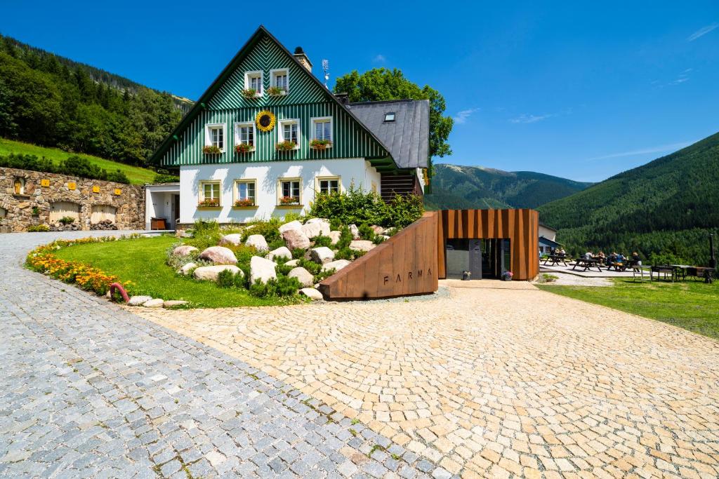 une maison avec un toit vert et une allée en briques dans l'établissement Pension Slunečnice & Restaurace Farma, à Špindlerův Mlýn