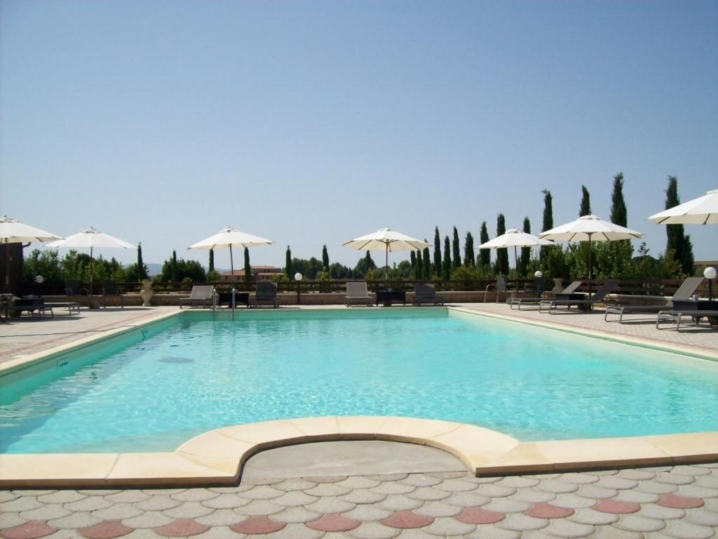 a large swimming pool with chairs and umbrellas at Il Vivaio in Tarquinia