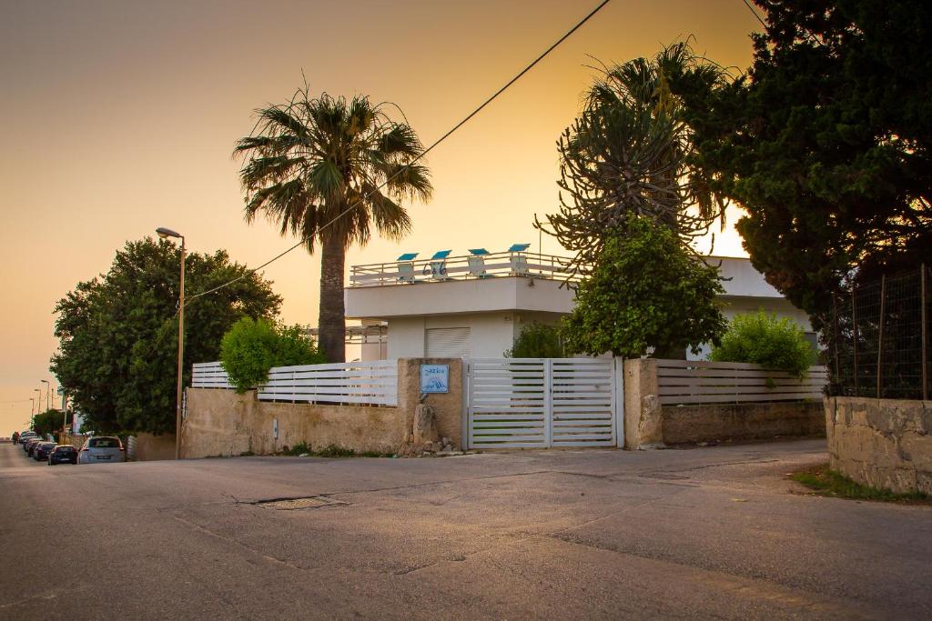 una casa con una valla blanca y palmeras en Jazira en Scoglitti