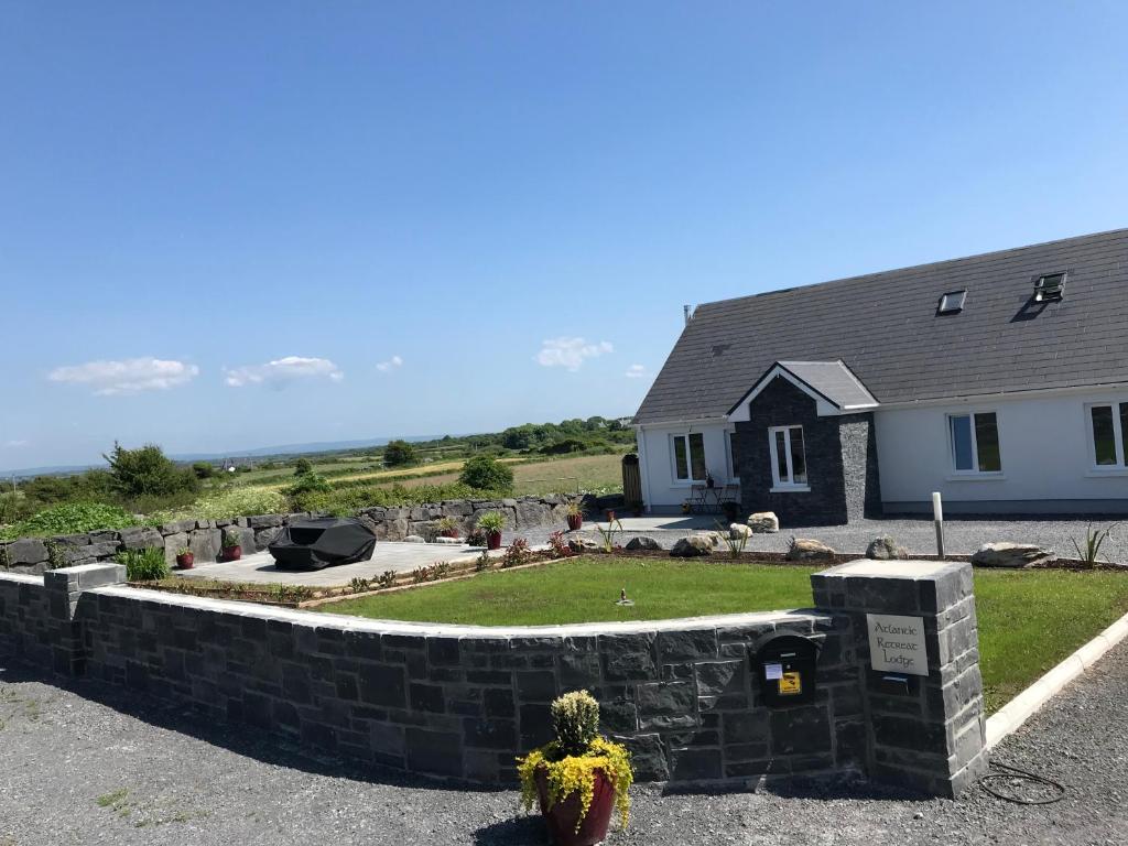 a house with a retaining wall in front of a yard at Atlantic Retreat Lodge in Kinvara