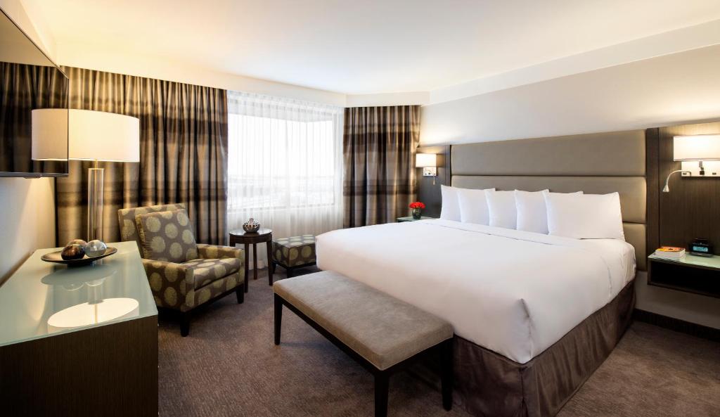 サスカトゥーンにあるSaskatoon Inn & Conference Centreの大きなベッドと椅子が備わるホテルルームです。