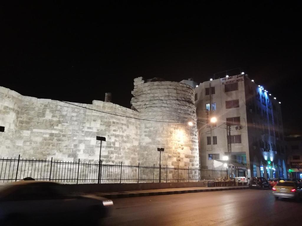 Un castillo grande por la noche con un coche pasando. en Al-Houriat Hotel, en Amán