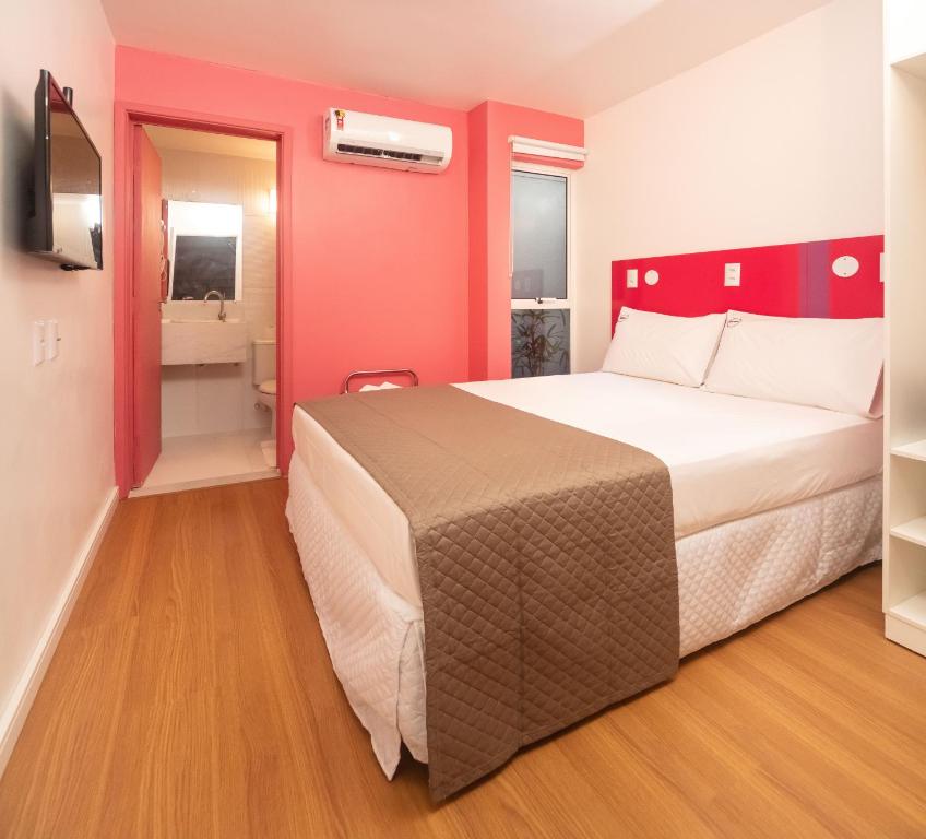 a hotel room with a large bed and a bathroom at Zuza Slim Suítes in Maceió