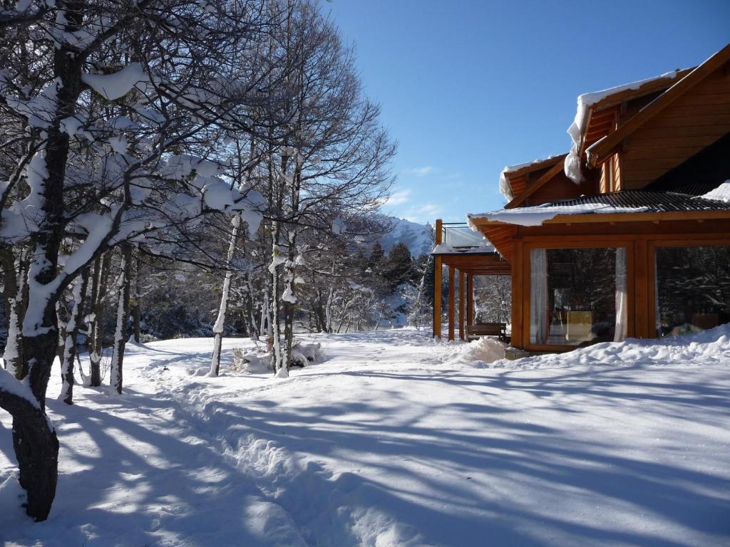 a snow covered path in front of a cabin at Rio Hermoso Hotel De Montaña in San Martín de los Andes