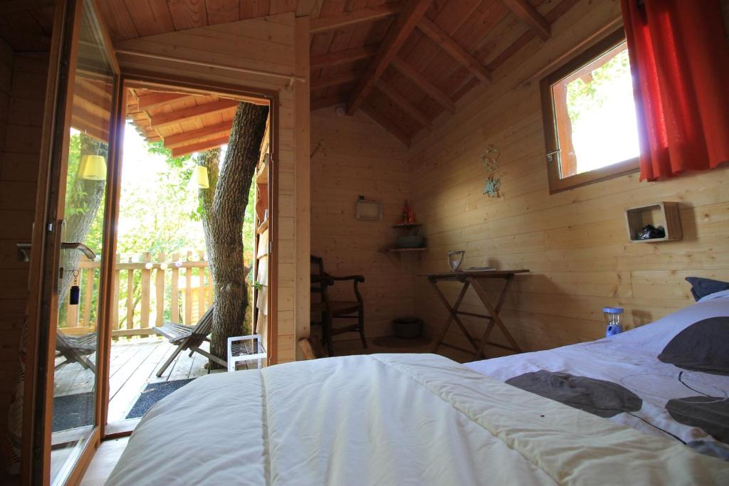 Saint-Antoine-de-BreuilhにあるNuits perchées à Laroqueの木造家屋内のベッドルーム(ベッド付)