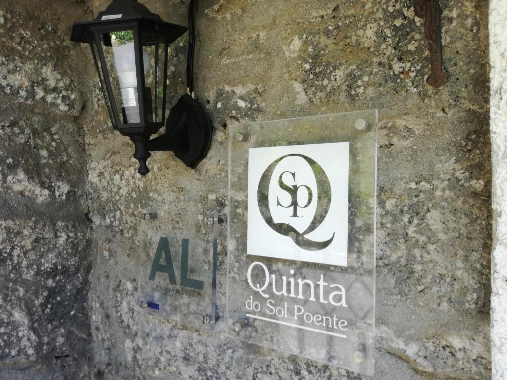 ein Straßenlicht und ein Schild an einer Steinmauer in der Unterkunft Quinta Do Sol Poente in Feteiras