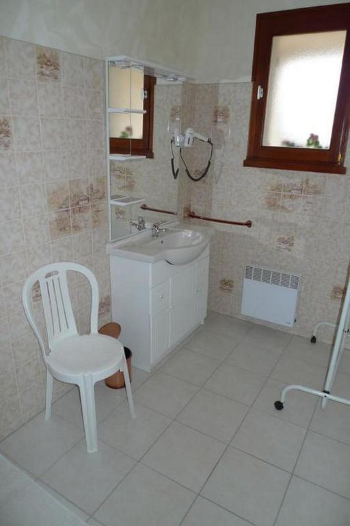 a white bathroom with a sink and a chair at Chambres d&#39;Hôtes Mazurier in Cozes
