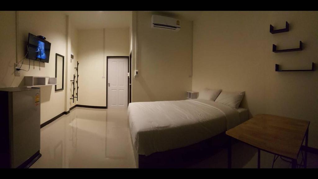 a white bedroom with a bed and a table at Ban Bunsawaeng Resort in Chaiyaphum