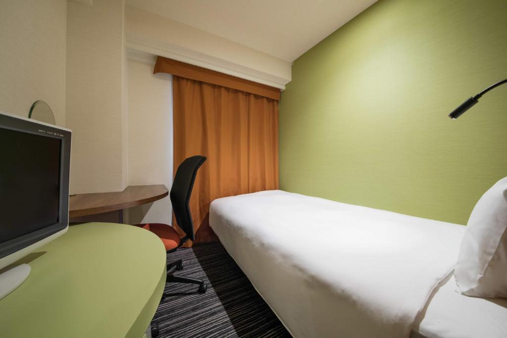 a hotel room with a bed and a desk with a tv at the b ikebukuro in Tokyo