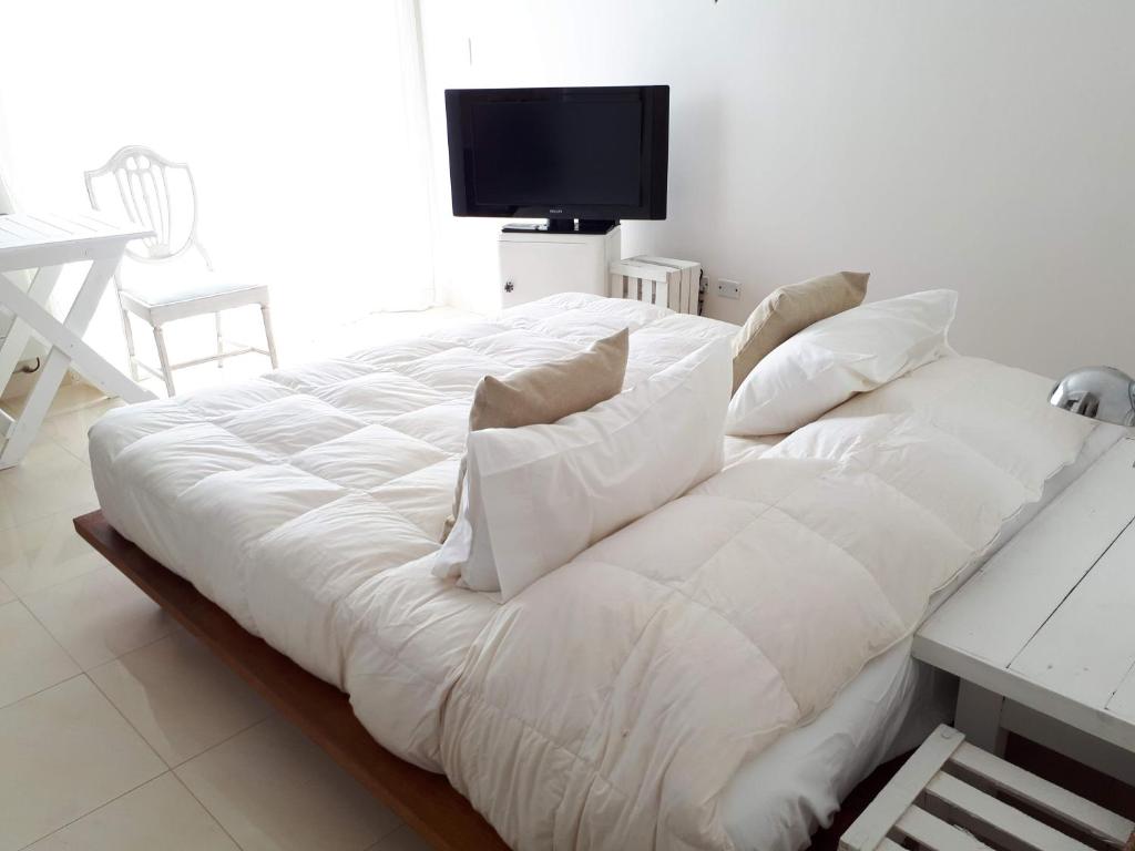 a large white bed with white pillows and a television at Altos del Sur in Santa Fe