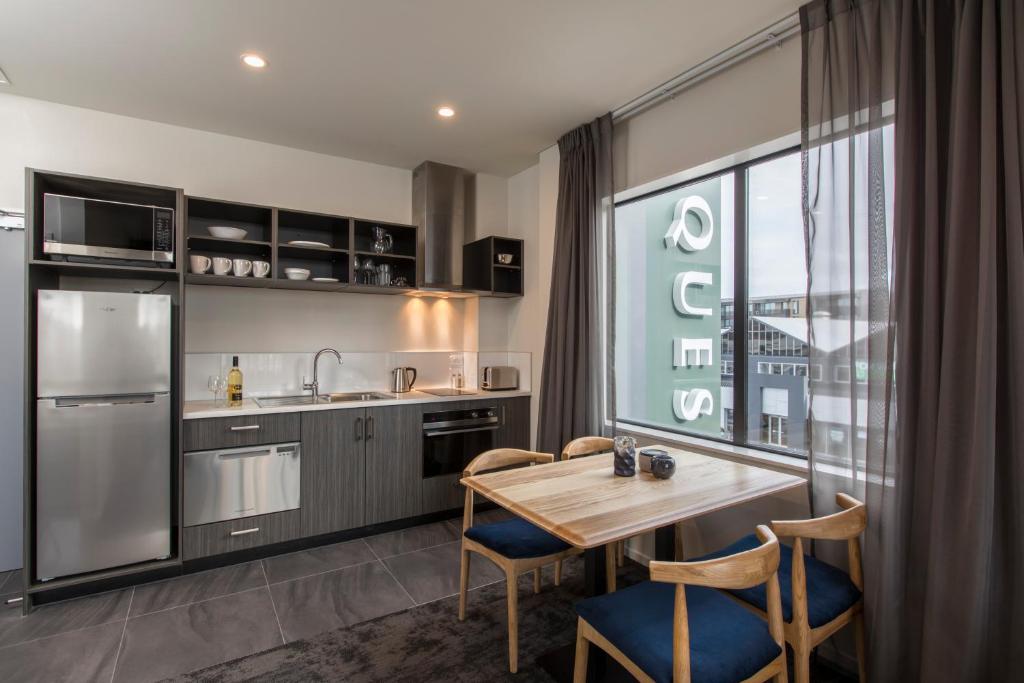 a kitchen with a table and chairs and a large window at Quest on Manchester Serviced Apartments in Christchurch