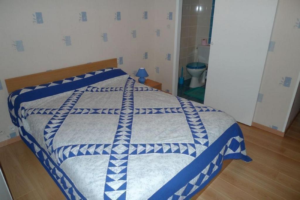 a bedroom with a bed with a blue and white comforter at Chambres d&#39;Hôtes Mazurier in Cozes