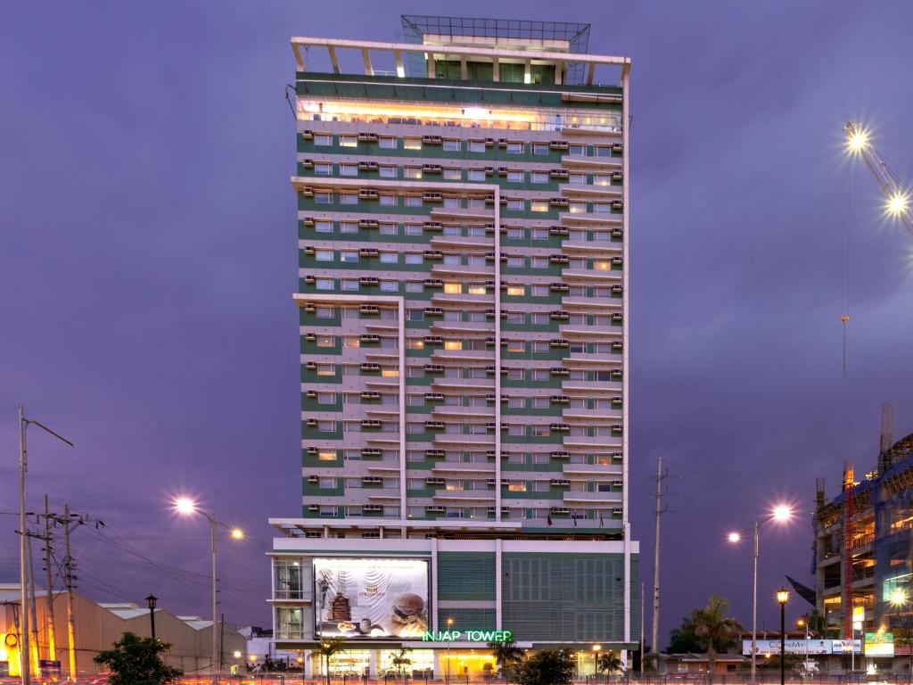 een hoog gebouw met een bord ervoor bij Injap Tower Hotel in Iloilo City