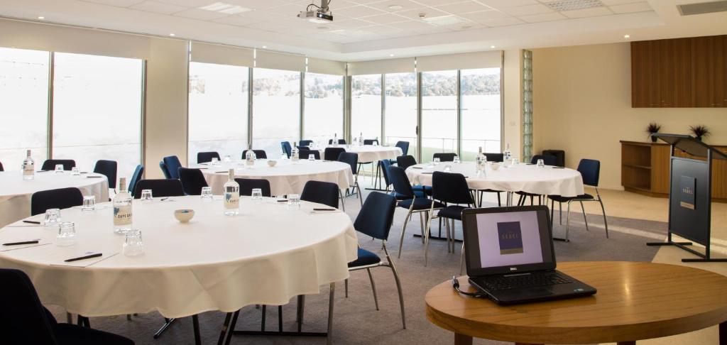 a room with white tables and chairs and a laptop on a table at The Sebel Launceston in Launceston