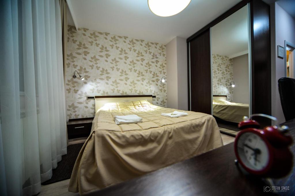 um quarto com uma cama com um espelho e um relógio em Garni Hotel 018 In em Niš