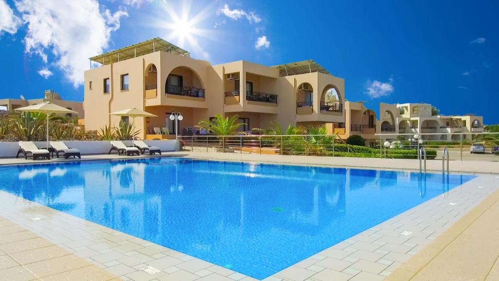 a large swimming pool in front of a villa at Nanakis Beach Apartments in Stavros