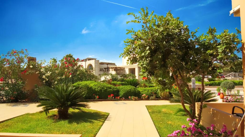 a garden with plants and trees and a building at Nanakis Beach Apartments in Stavros