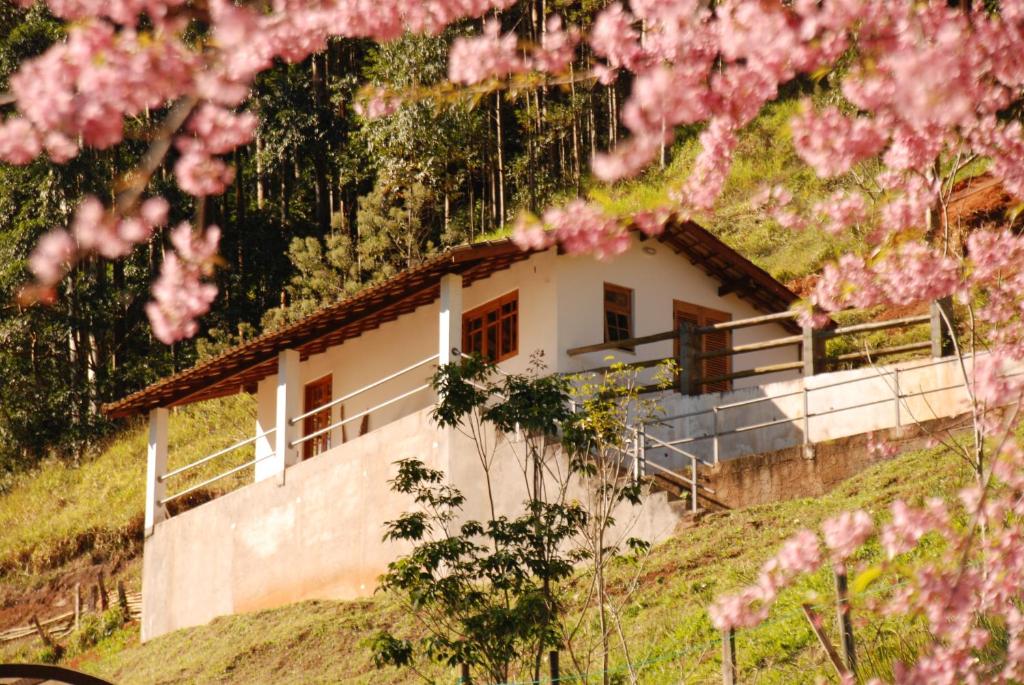 uma casa numa colina com flores cor-de-rosa em Chalés de Valfena em São Francisco Xavier