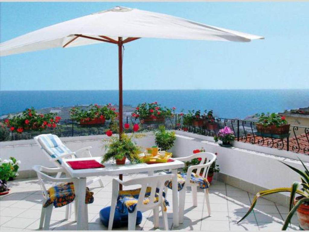 a white table and chairs with an umbrella on a balcony at Casa Bellavista in Terzorio