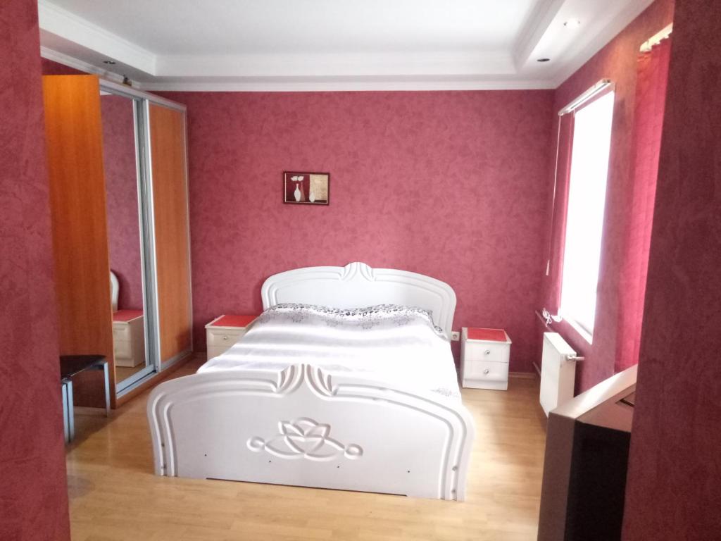 1 dormitorio con 1 cama blanca en una pared rosa en Домик у моря en Odesa