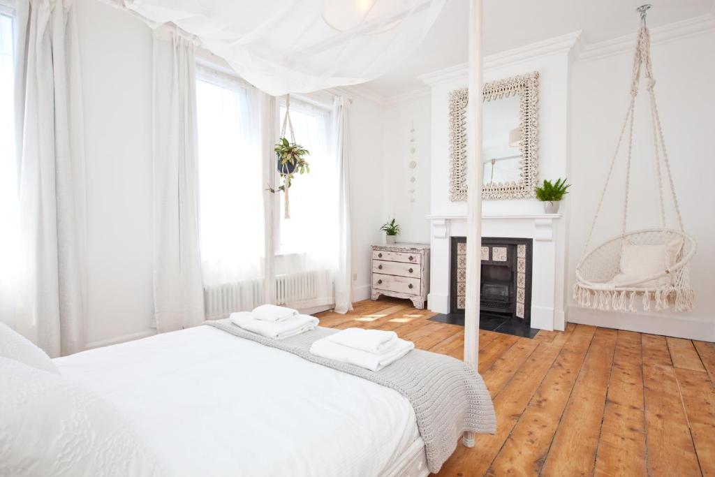 een witte slaapkamer met een bed en een open haard bij Spacious Retreat With Sunny Garden in Brighton & Hove