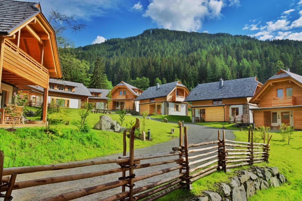 a fence in a village with houses and a mountain at Trattlers Hof-Chalets in Bad Kleinkirchheim