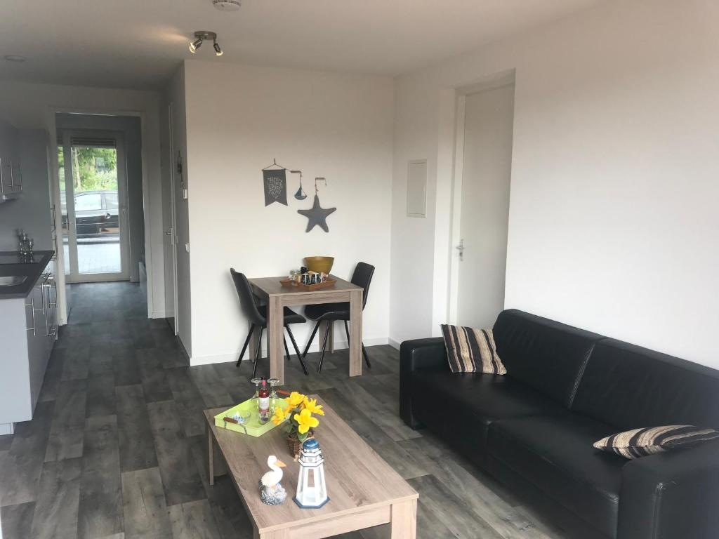 a living room with a black couch and a table at Gerbrandion Appartement Verhuur in Vlissingen