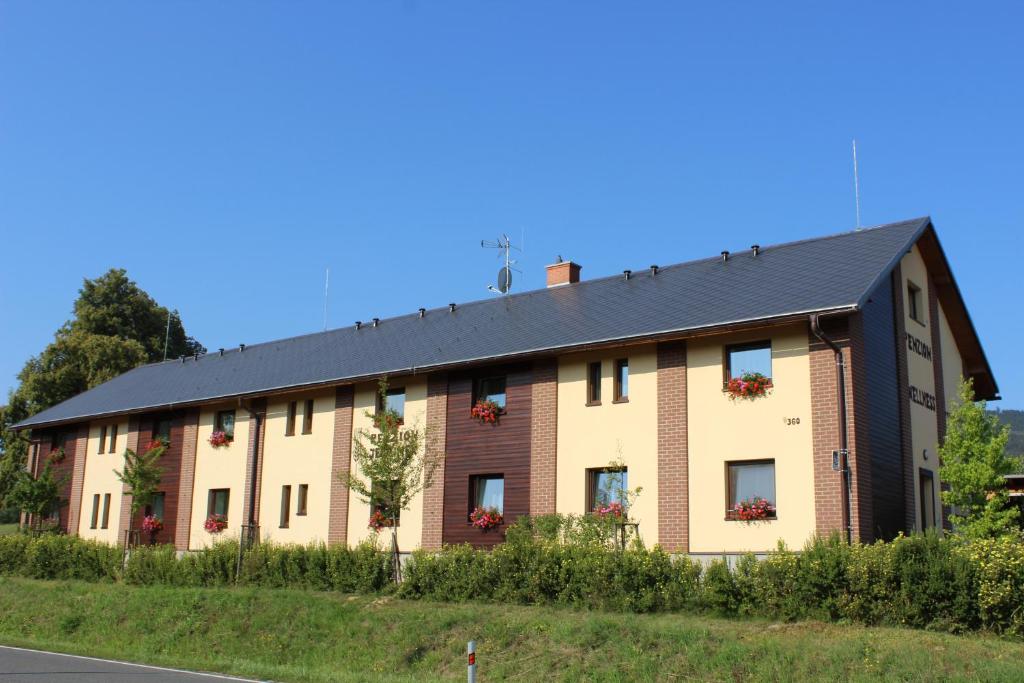 duży ceglany budynek z czarnym dachem w obiekcie Penzion Ječmínek w mieście Červená Voda