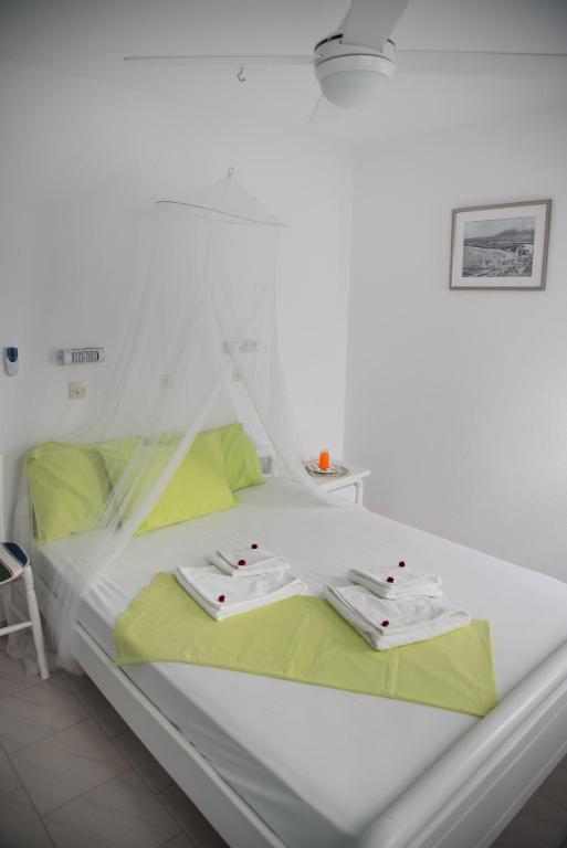 a white bed in a white room with green sheets at Paroscarmel studio-apartment in Logaras